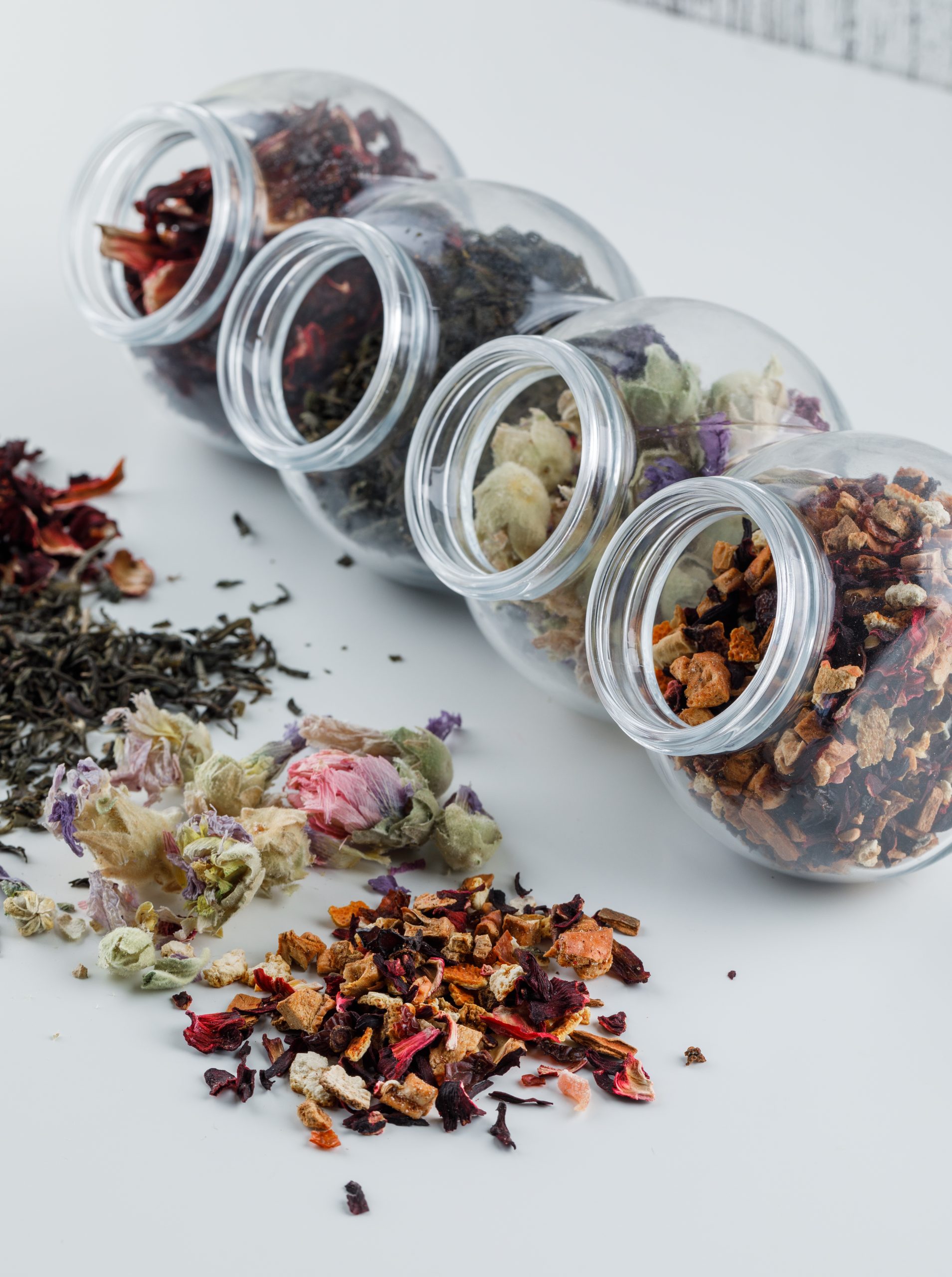 Assorted dried herbs in plastic jars high angle view on white and grunge background