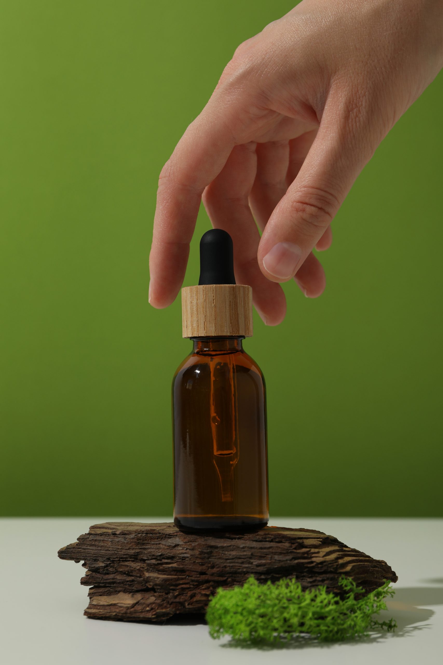 moss tree bark bottle serum hand green background scaled